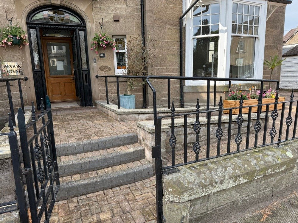 The Broughty Ferry clinic has a stone façade, arched wooden doorway, brick steps, black railings, white-framed windows and flower boxes.